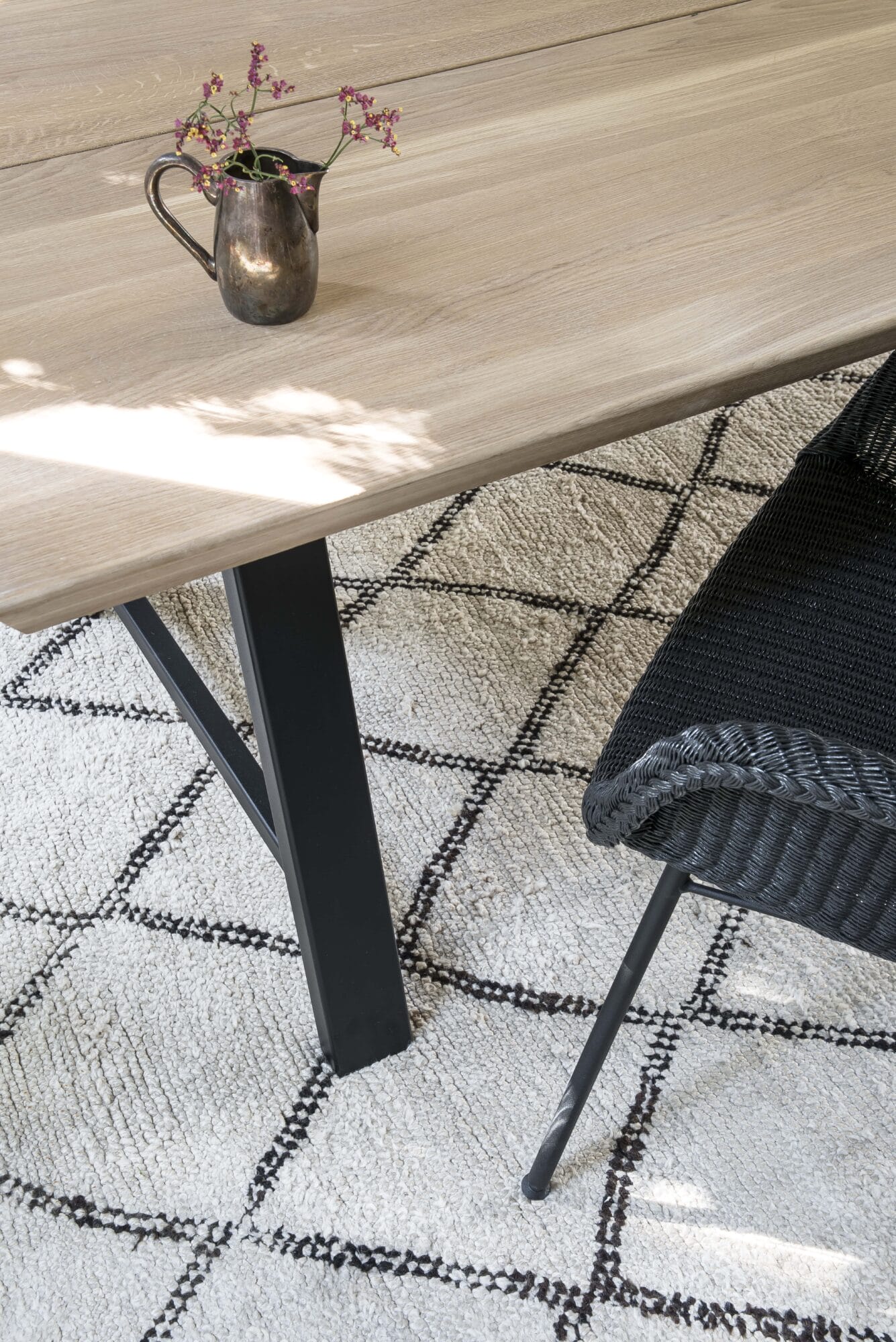 Une table à manger avec un tapis noir et blanc et une chaise Avril.